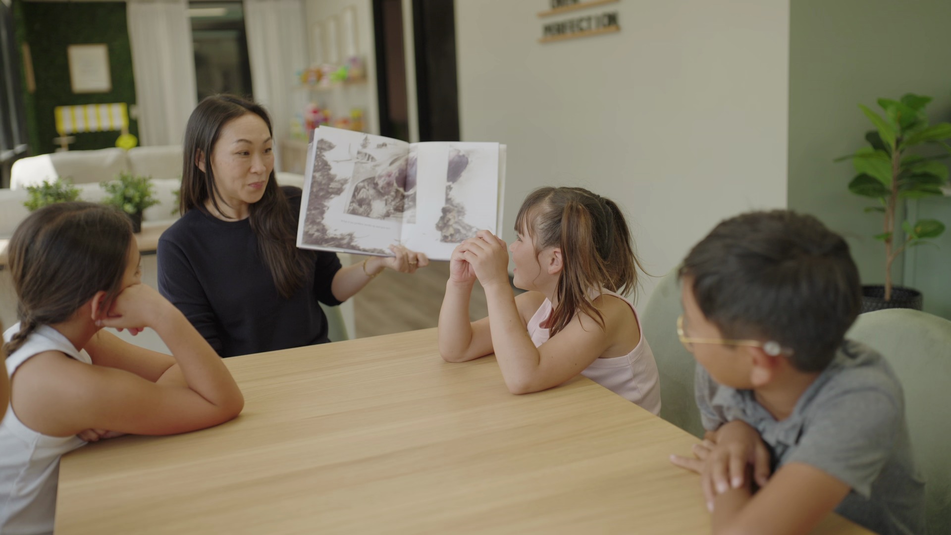 A JLC therapist reads a picture book aloud to three children around a table